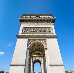 Fototapeta na wymiar Front view of the northern pillar of the Arc de Triomphe in Paris, France, illuminated by the morning sunlight under a blue sky.