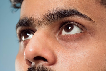 Close up portrait of young hindoo man's face with brown eyes looking up or at side. Human emotions,...