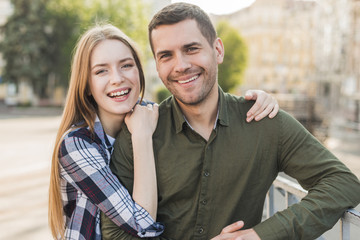 Fototapeta premium Young smiling couple standing near railing looking at camera