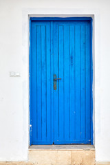 Old blue wooden door of a traditional Mediterranean house painted in white