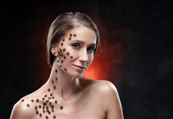 Beautiful smiling girl with naked shoulders. Coffee beans were artistically stuck to the healthy...