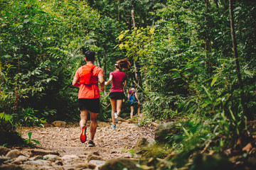 Runners. Young people trail running on a mountain path. Adventure trail running on a mountain. Athletic attractive people running enjoying the sun exercising their healthy lifestyle.