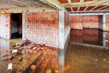 The basement of a building under construction is filled with dirty flood water