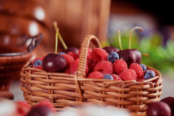 Raspberries and blueberries in basket with sweet cherry Summer and healthy food selective focus.