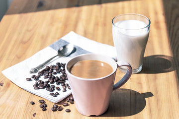 Cup of coffee and glass of almond milk on wooden table, close up