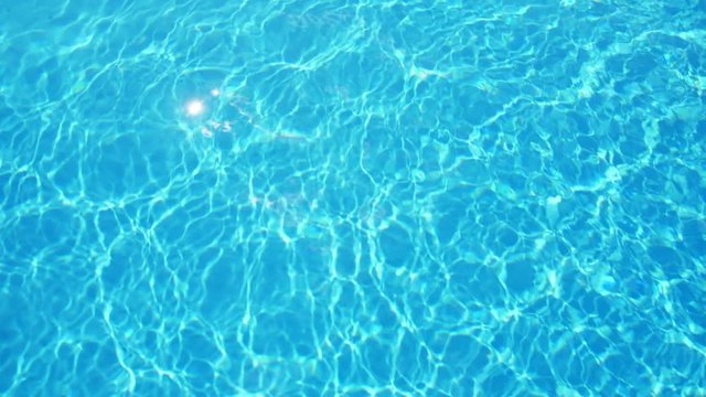Sky-blue waters with sun rays playing in a swimming pool in slo-mo