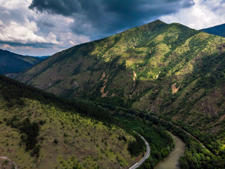 Aerial view of river through forest and mountains, cloudy sky. Ibar river in Serbia