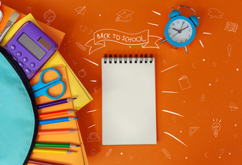 Concept back to school. Full turquoise School Backpack with supplies on orange background. FLat lay.
