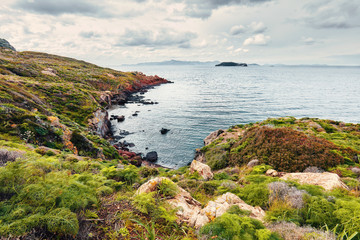 Moody view of Gumusluk bay in Bodrum, Mugla, Turkey on a cloudy winter day. Beautiful calm sea, meadow and sky landscape.