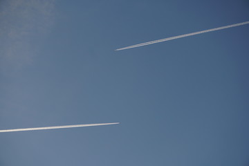 estelas blancas sobre cielo azul de dos aviones reactores que van en sentido opuesto 
