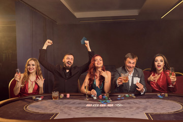 Group of a young wealthy friends are playing poker at a casino.