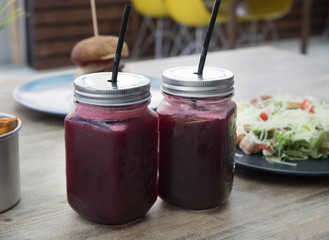 Currant Lemonade in mason jar with meat burger, french fries and caesar salad. Fast food cafe