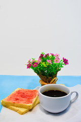 Obraz na płótnie Canvas Bread topped with jam and a cup of coffee, placed beside from a bouquet of flowers