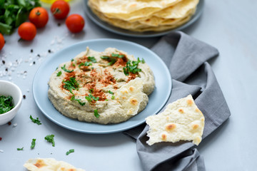 Eggplant dip baba ganoush (mutabbal) with herbs and paprika on gray wooden background. Selective focus. Traditional arabian food