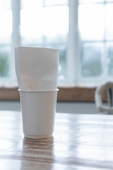 closeup of white takeaway paper cup with tissue napkin on wooden table.