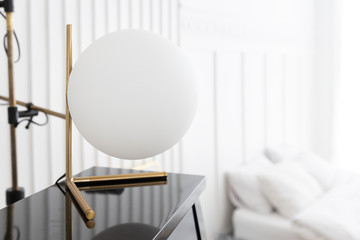 closeup of interior sphere white ball lamp on piano with blurry bed room background.
