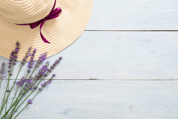 Flatlay feminine desk with straw hat and lavender flowers on rustic blue wooden background. Flat...