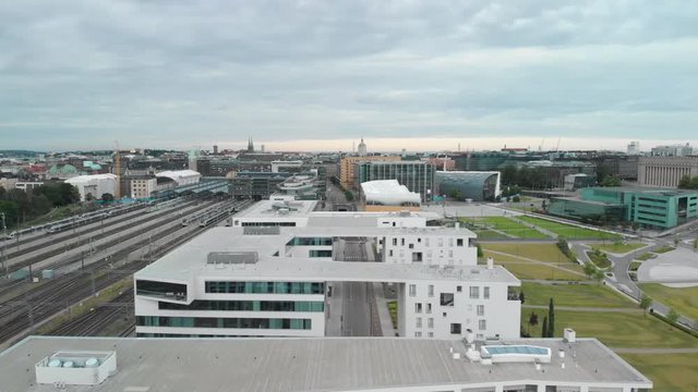Aerial, drone shot, over buildings,overlooking railway tracks,the train station, the Oodi library and the downtown, on a cloudy, summer day, in Uusimaa, Finland