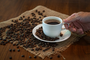 Hot coffee cup with roasted coffee beans on wood table