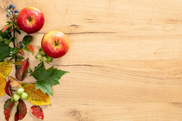 Flatlay composition with autumn fallen leaves and apple on wooden background. Autumn frame. Flat lay, top view, copy space.