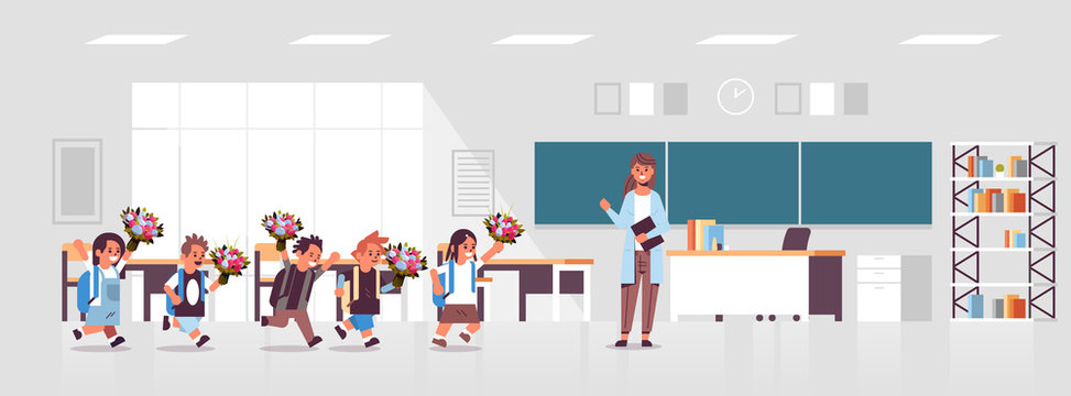 Pupils Giving Flowers To Female Teacher Standing In Front Of Board In Classroom Education Back To School Concept Modern Class Room Interior Flat Horizontal Full Length