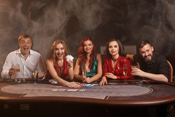 Group of a young wealthy friends are playing poker at a casino.