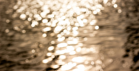 Bokeh of the orange light of the sun reflects the waves in the evening.