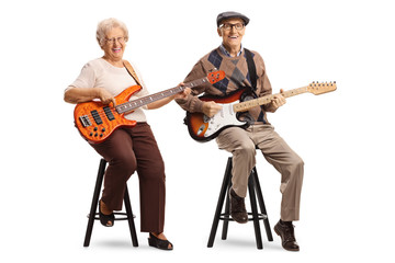 Fototapeta premium Senior man and woman sitting and playing electric guitars