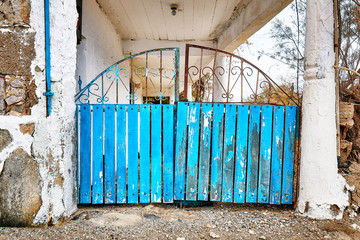 Retro wooden and rusty wrought iron blue entrance fence door of a rural house