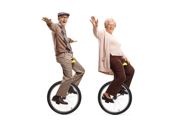 Elderly man and woman riding unicycles and smiling at the camera © Ljupco Smokovski