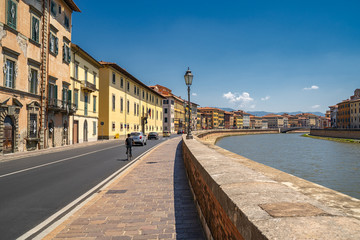 Naklejka na ściany i meble Cityscape view of Arno River in Pisa city old town in a sunny day, Italy