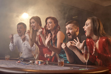 Group of a young wealthy friends are playing poker at a casino.