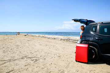 A woman weraing sunglasses and a hat in the summer car on the beach and ocean view..