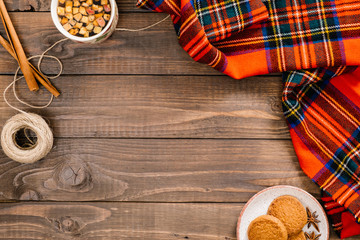 Flatlay autumn composition. Frame of red plaid, tea cup, cinnamon sticks, rope, cookies on wooden background. Flat lay, top view, copy space. Cozy home desk, hygge, autumn fall concept