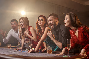 Group of a young wealthy friends are playing poker at a casino.