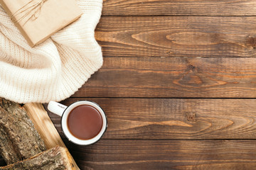 Fototapeta na wymiar Autumn composition. Frame made of white knitted sweater, cup of tea, firewood on wooden background. Cozy autumn or winter holiday concept. Flat lay, top view, copy space