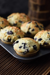 Homemade blueberry muffins on oak board close up with natural lighting side view