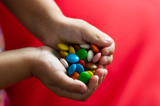 Sweet colorful round candies in child hands in shape of heart - Powered by Adobe