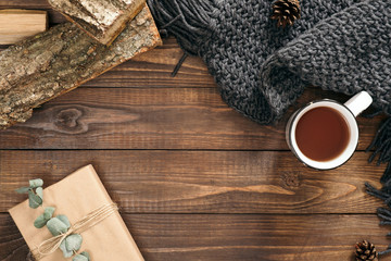 Autumn composition. Cup of tea, women fashion scarf, gift box, firewood on wooden background. Flat lay, top view, copy space. Scandinavian hygge concept.