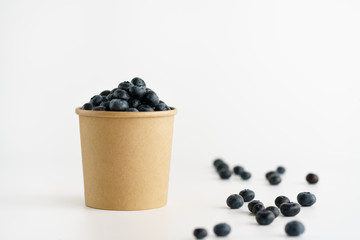 Fototapeta na wymiar Fresh organic blueberries in a paper cup on a white background.
