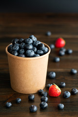 Fresh organic blueberries and strawberries in a paper cup