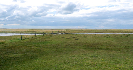 Fototapeta na wymiar Laesoe / Denmark: Tidal creek in the wide salt marsh landscape on „Kringelroen“ in the south of the Kattegat island