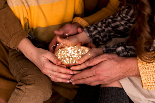 The Young Family Is Holding A Round Tin Box With A Garland. Christmas Time..