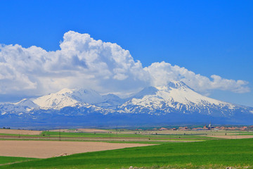 Snowy peaks of mountains visible from the green valleys of Cappadocia.