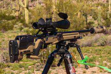 Suppressed Precision Bolt-Action Rifle on shooting tripod at outdoor range