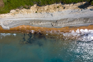 Aerial view of beautiflul rocky cliff and sandy beach by the ocean.