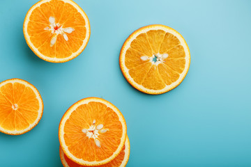 Round slices of juicy orange on a blue background, top view as a background substrate. Food background