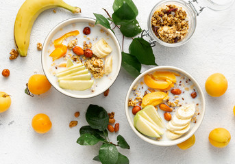 Granola bowl with fruits, nuts, milk and peanut butter in bowl on a white background. Healthy breakfast cereal top view