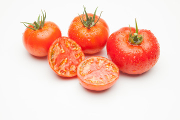 Conjunto de tomates maduros y medio tomate abierto por la mitad.
