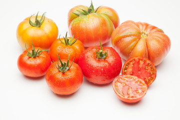Conjunto de tomates maduros y medio tomate abierto por la mitad.